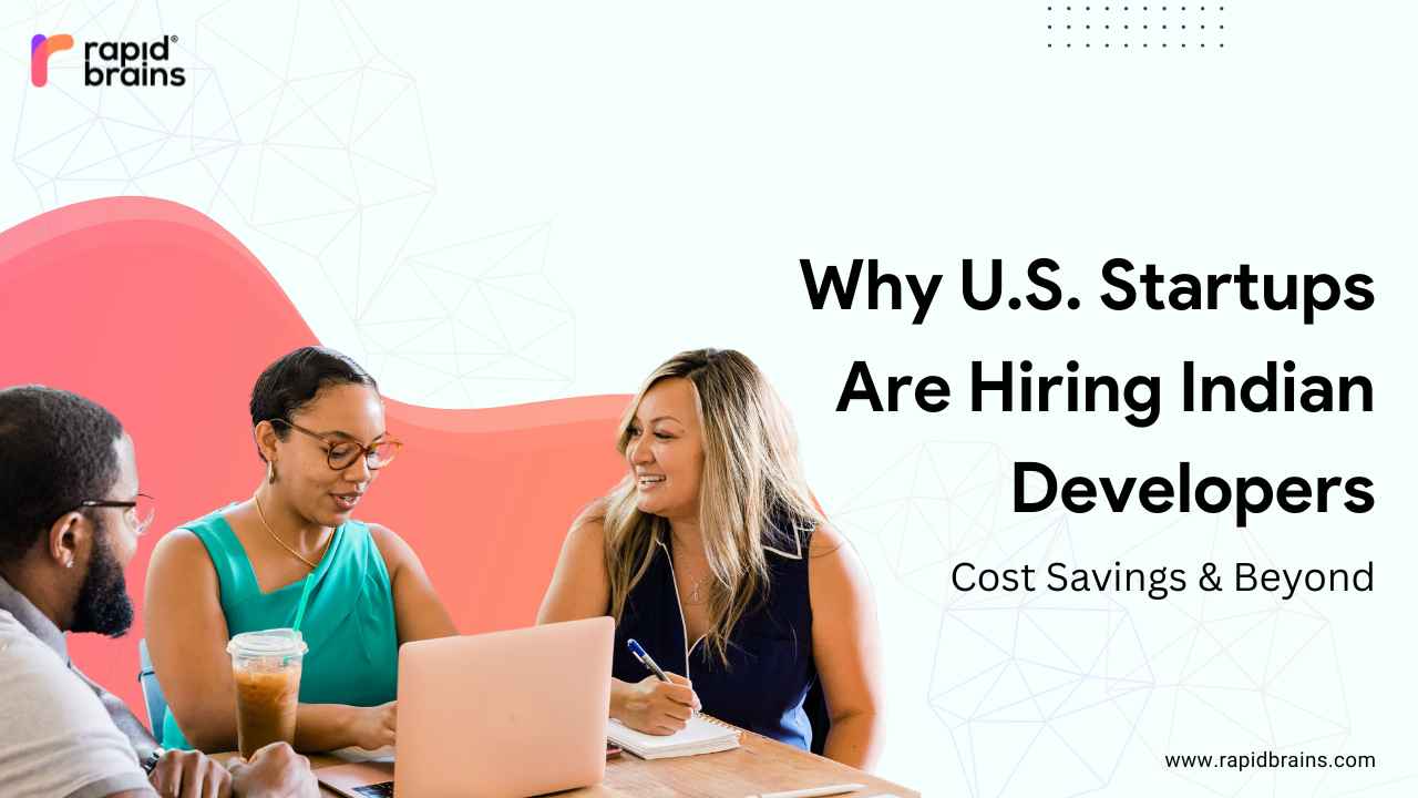 Three professionals, two women and one man, sit at a table collaborating with a laptop and drinks. The background features a white and orange abstract design with geometric patterns. Text on the right reads: "Why U.S. Startups Are Hiring Indian Developers – Cost Savings & Beyond." The RapidBrains logo appears in the top left corner.